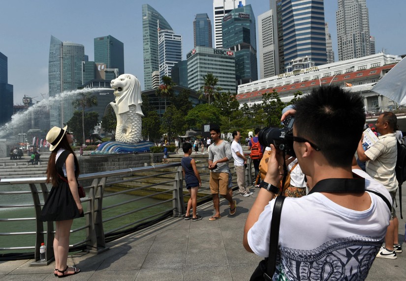 Du kh&aacute;ch Trung Quốc chụp ảnh với tượng Merlion ở Singapore. Ảnh: AFP