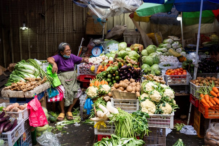 Một chủ sạp rau quả tại khu chợ ở Manila, Philippines. Ảnh: Reuters