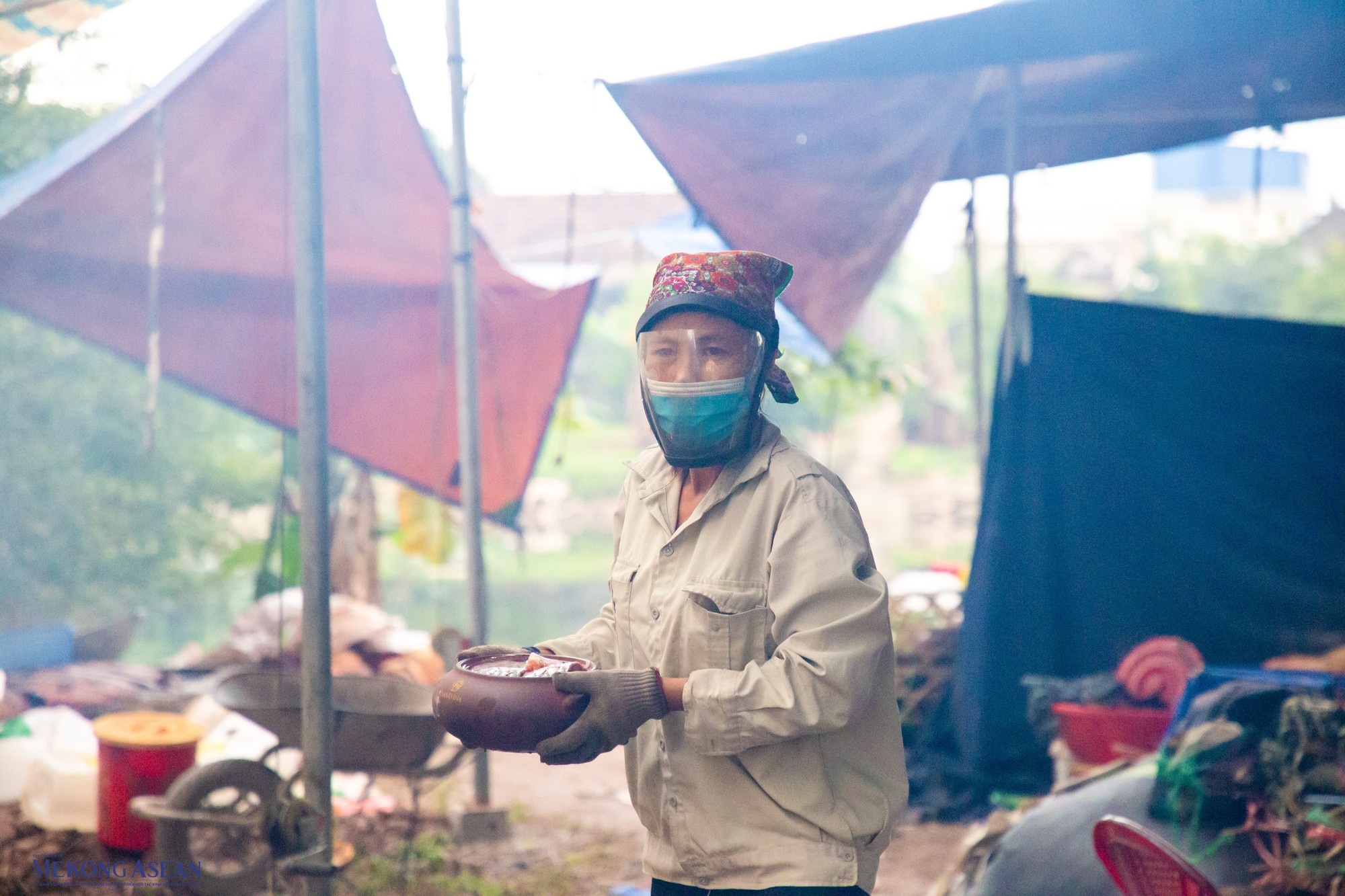 Người kho c&aacute; phải đeo mặt nạ để hạn chế kh&oacute;i từ củi nh&atilde;n ảnh hưởng đến mắt. Ảnh: Thảo Ng&acirc;n.