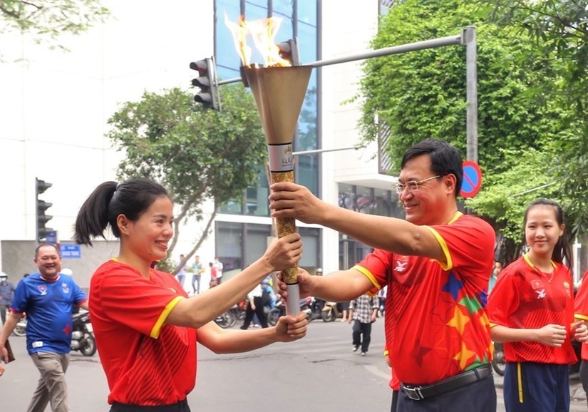 Đuốc được truyền tay đến vận động vi&ecirc;n điền kinh Nguyễn Thị Huyền để c&ugrave;ng c&aacute;c vận động vi&ecirc;n rước quanh hồ Ho&agrave;n Kiếm. Ảnh: TTXVN