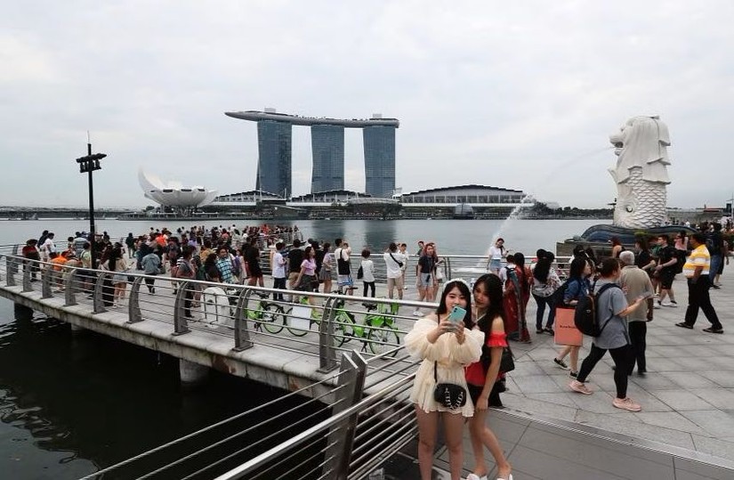 Kh&aacute;ch du lịch chụp ảnh gần biểu tượng sư tử Merlion, Singapore. Ảnh: Straits Times