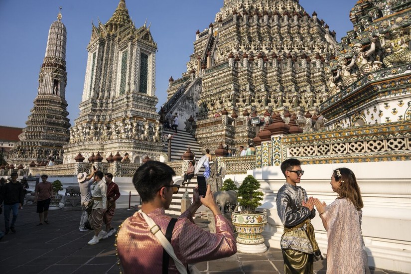 Kh&aacute;ch du lịch trong trang phục truyền thống Th&aacute;i Lan chụp ảnh tại ch&ugrave;a Wat Arun ở Bangkok, Th&aacute;i Lan. Ảnh: Bloomberg