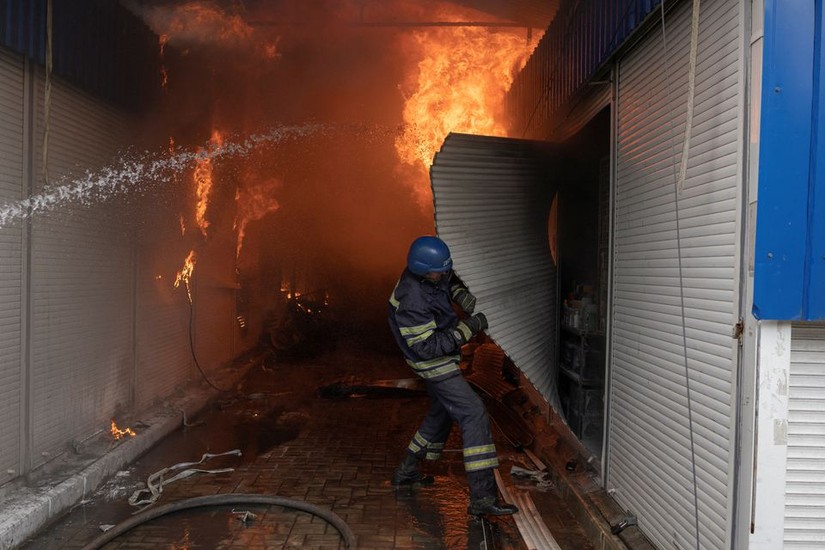 L&iacute;nh cứu hỏa đang dập tắt đ&aacute;m ch&aacute;y do tr&uacute;ng ph&aacute;o k&iacute;ch tại khu chợ ở Sloviansk, tỉnh Donetsk, Ukraine, ng&agrave;y 5/7. Ảnh: Reuters