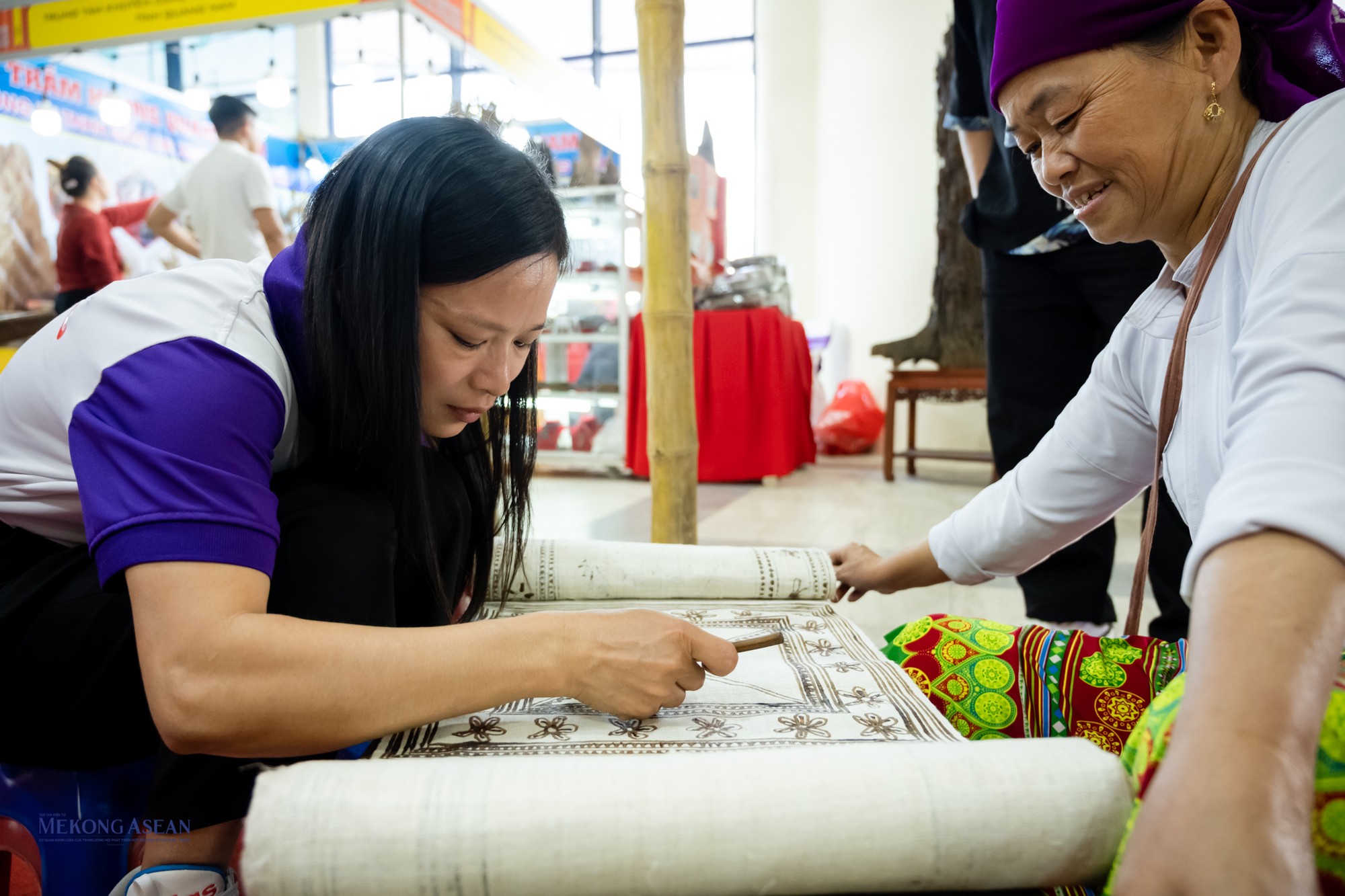 Tới tham dự hội chợ tại H&agrave; Nội, du kh&aacute;ch c&oacute; thể trực tiếp tham gia c&ocirc;ng đoạn dệt vải cũng như t&ocirc; vẽ c&aacute;c hoa văn họa tiết tr&ecirc;n bề mặt miếng vải,