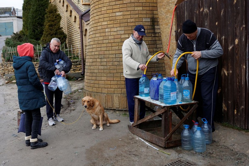 Người d&acirc;n sinh sống gần s&ocirc;ng Dnipro đổ đầy nước v&agrave;o chai để sử dụng. Ảnh: Reuters