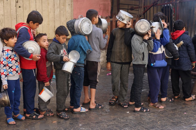 Trẻ em Palestine xếp h&agrave;ng nhận thức ăn do một bếp từ thiện nấu ở Rafah, miền nam Gaza, ng&agrave;y 14/12. Ảnh: Reuters